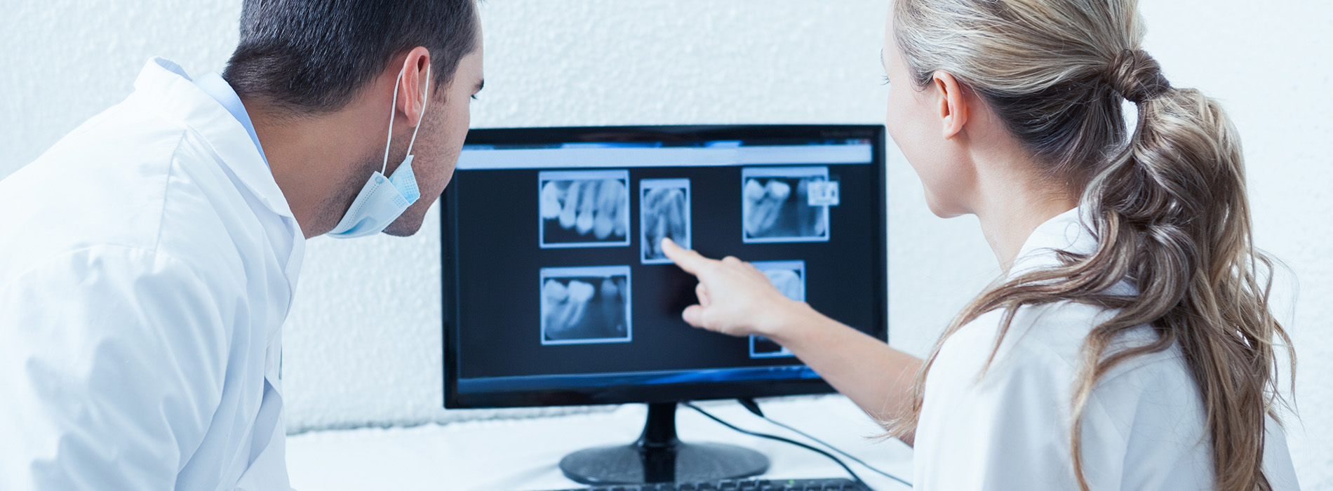 An image of a medical professional showing a patient s X-ray on a screen to the patient, who is seated and attentively looking at it.