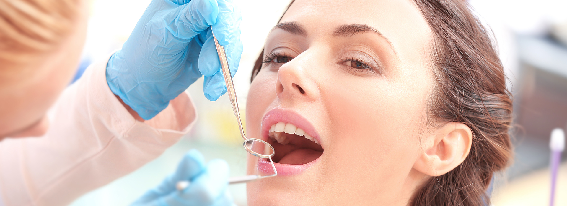 A woman receiving dental care, with a dental hygienist performing a procedure on her teeth.
