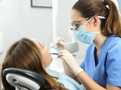 A dental hygienist is performing a cleaning procedure on a patient s teeth, with the patient seated in a dental chair and wearing protective eyewear.
