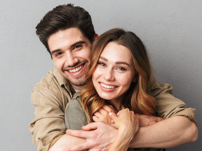 A man and a woman hugging, smiling, and posing for the camera.