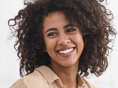 Woman with curly hair and a smile, looking directly at the camera.